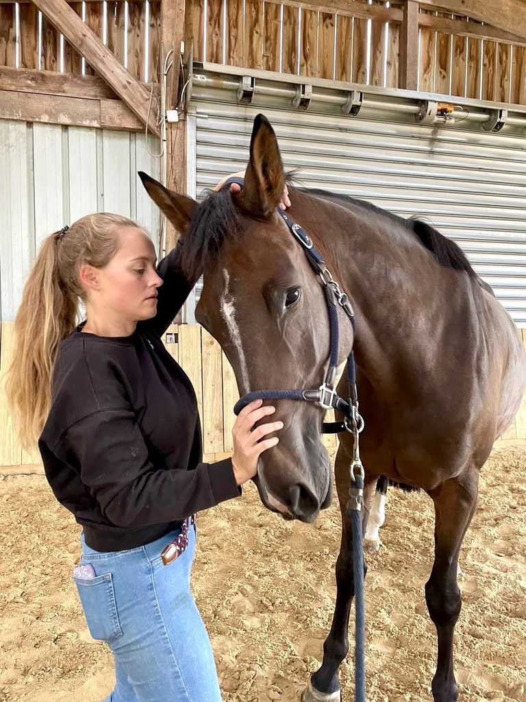 Agathe Bouguet caressant un cheval brun en manège
